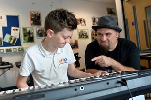 Boy playing keyboard to teacher