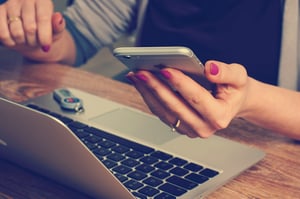 lady working at laptop holding mobile