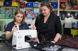 Girl being shown how to use a sewing machine