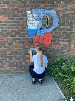 Girl drawing mural on brick wall using chalk